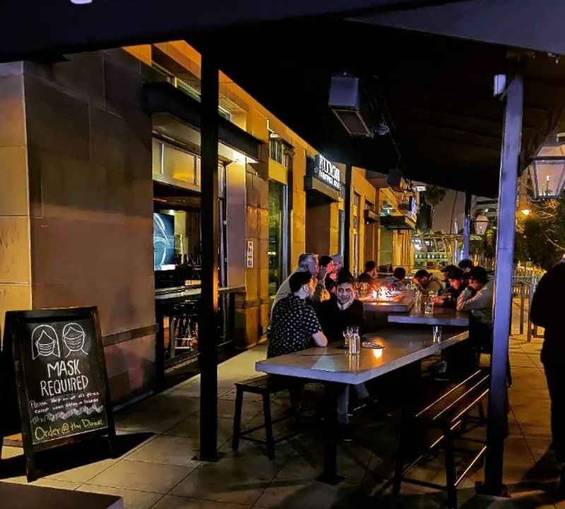 people sitting at tables outside of a restaurant