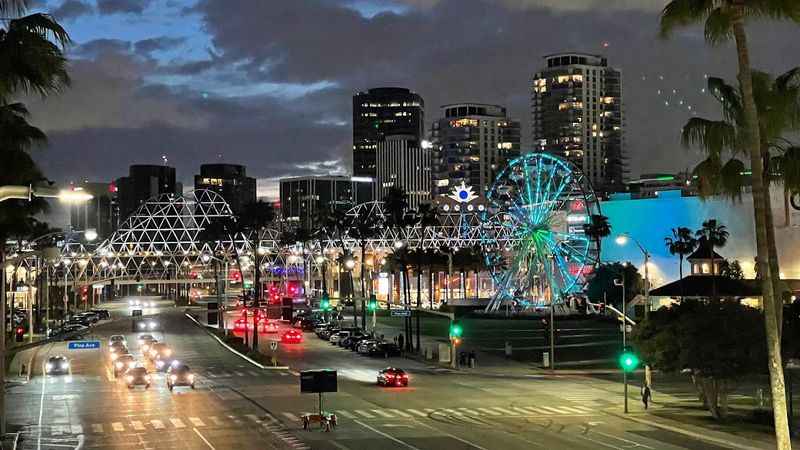 a city street with palm trees and a ferris