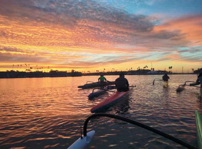 man paddling on a paddle board in the water at sunset