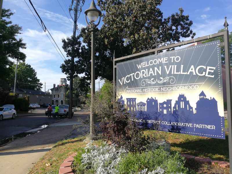 a sign for a village with a city in the background