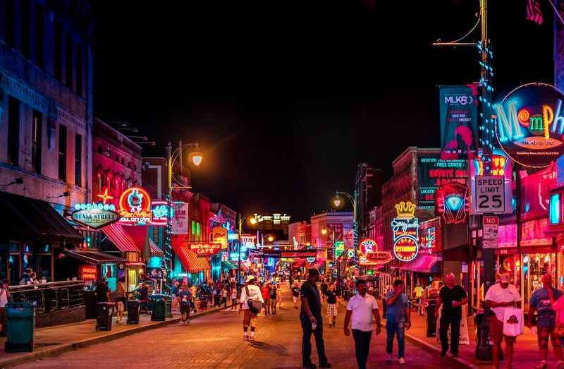 a street filled with neon signs and people walking down it