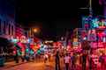 a street filled with neon signs and people walking down it
