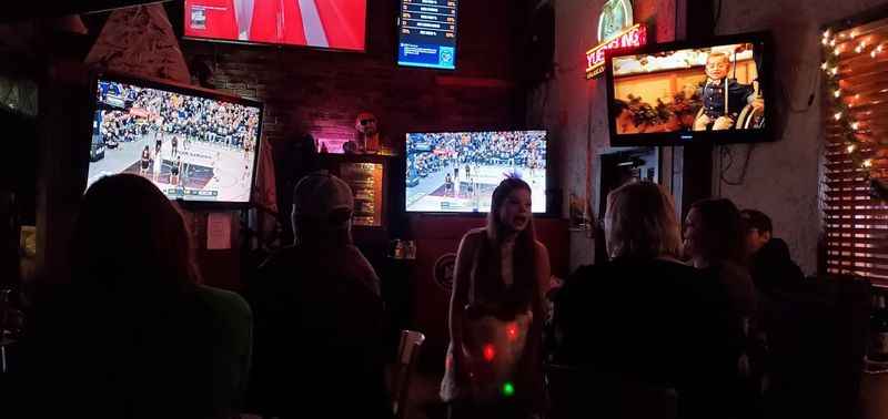 people watching a game on tvs in a bar