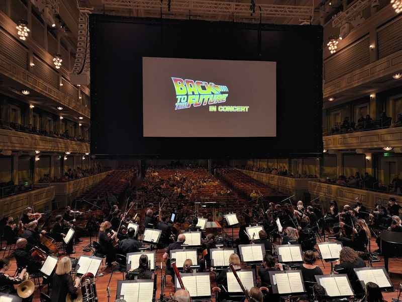 orchestra in large auditorium with screen in background