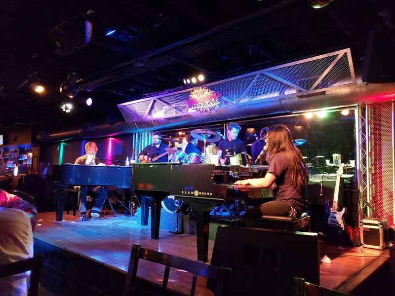 a woman playing a piano on stage in a bar