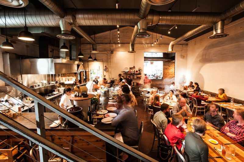 people sitting at tables in a restaurant with a staircase