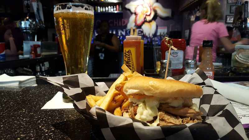 there is a sandwich and fries on a table with a beer