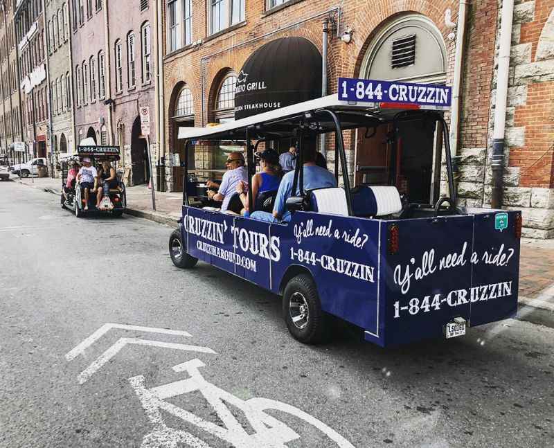 people riding in a small blue bus on the street