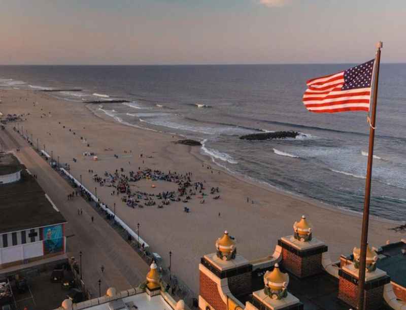 a flag on the top of bstructure near the beach at sunset