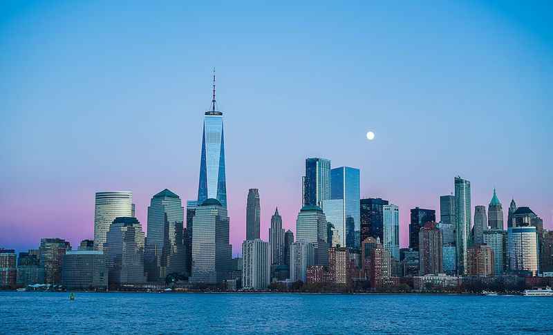 the moon rises over the tall buildings