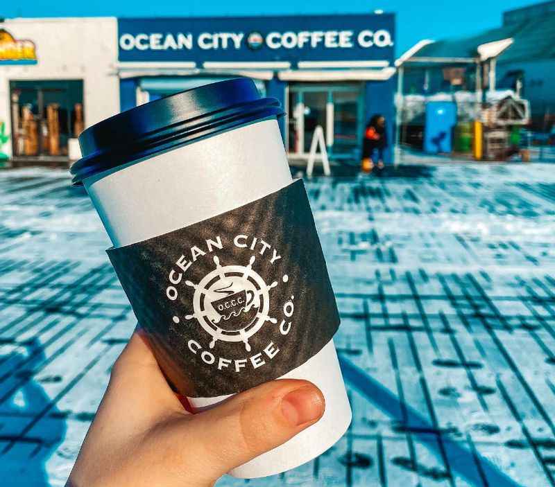 a hand holding a coffee cup with the ocean city coffee logo on it