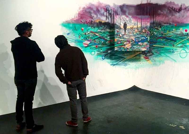 painting on the wall with two people looking at it