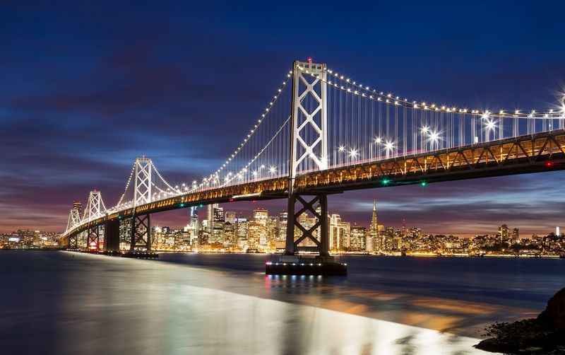 a bridge over water with a city in the background