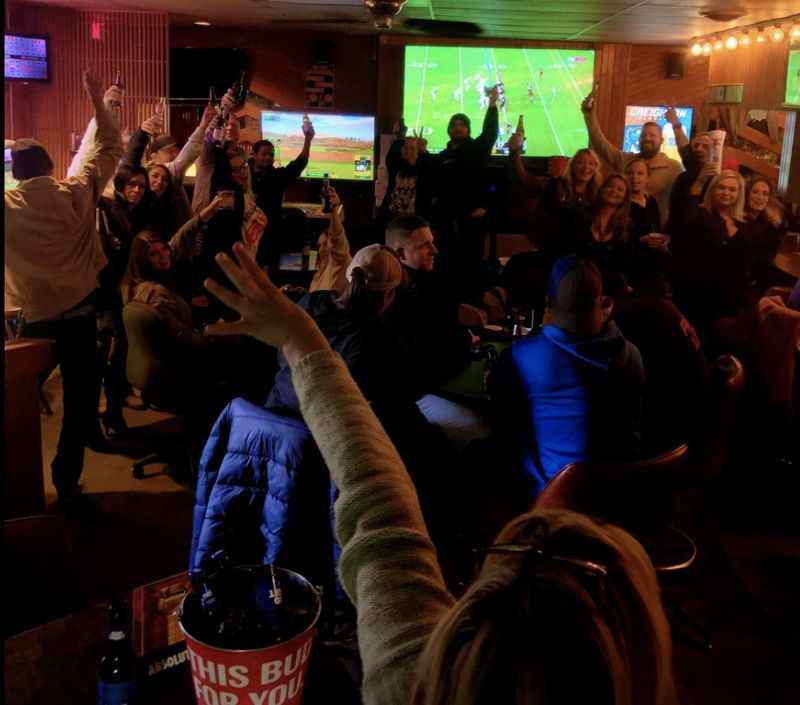 a group of people are cheering in a bar