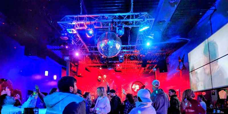 a crowd of people standing around a room with a dj