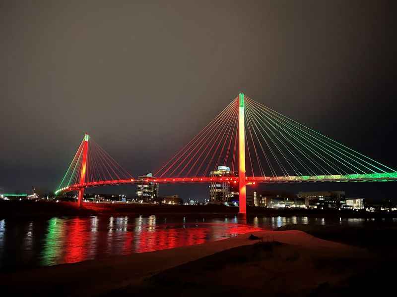 a bridge with lights and a river in the background