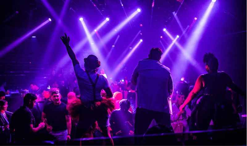 a group of people on stage with purple lights