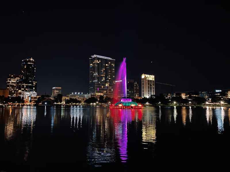 a city skyline with a fountain lit up at night