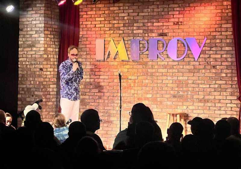 a man on stage with a microphone and a brick wall