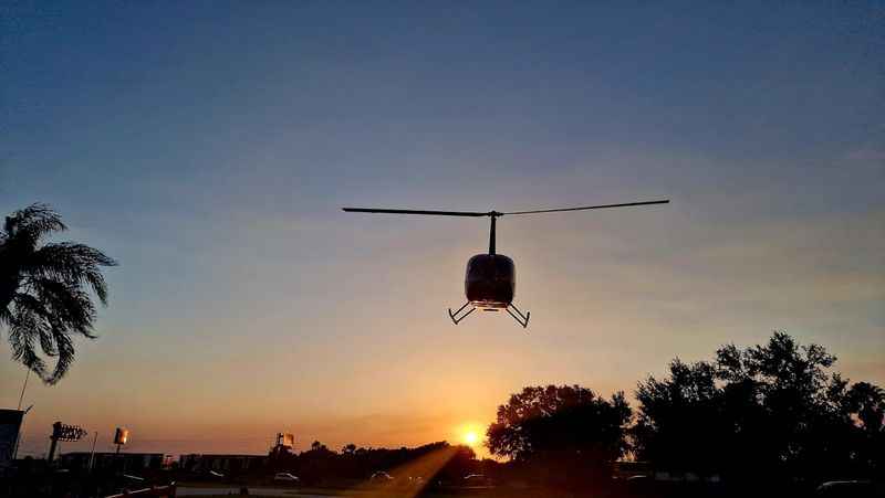 a helicopter flying over a street at sunset