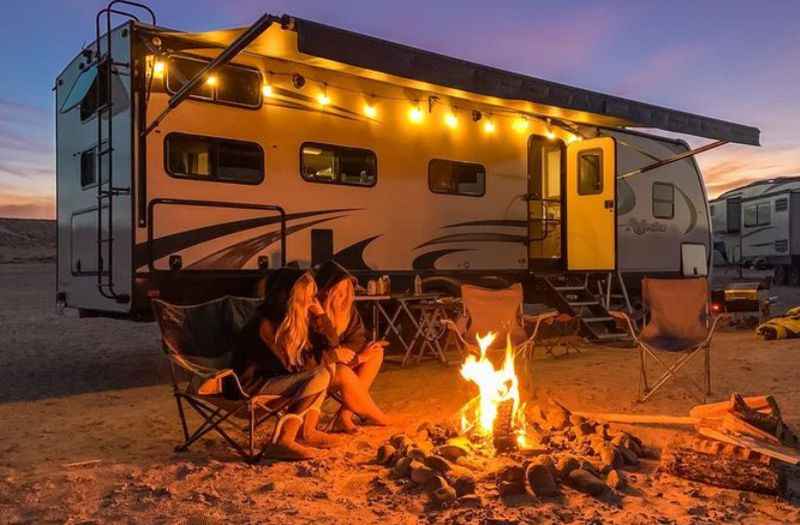 a woman sitting in front of a camper at night