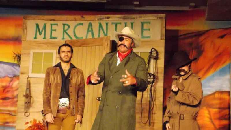 a man in a hat and coat standing on a stage