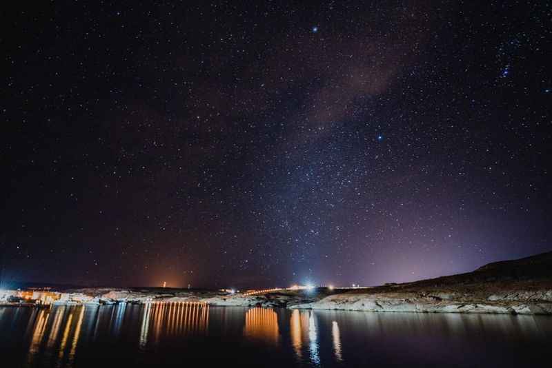 Beautiful night sky reflects the lights on the water