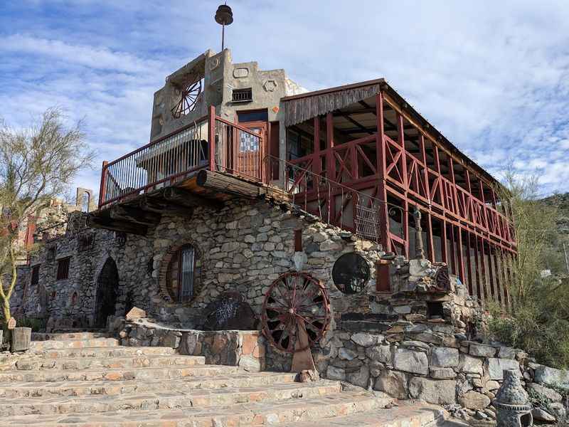 a stone building with a red roof and railing