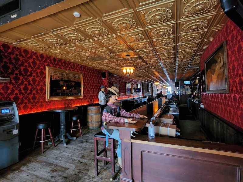 a man sitting at a bar with a red wallpaper