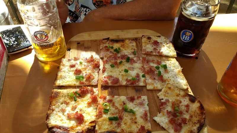 a person sitting at a table with a pizza and beer