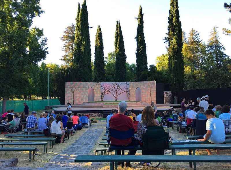 people sitting on benches in front of a stage