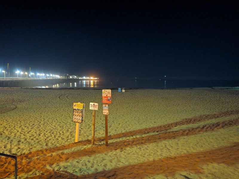 a beach with a sign and a beach chair