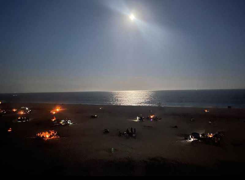 a beach with a fire pit and a full moon