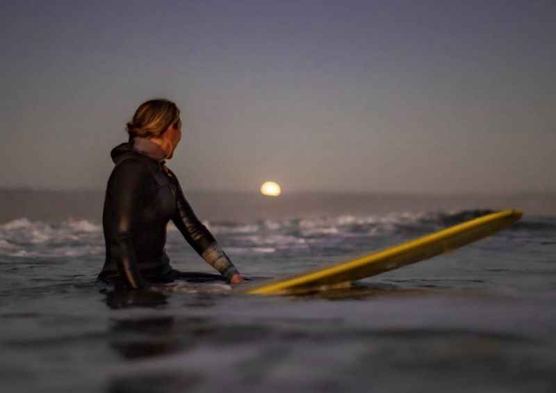 a woman in a wet suit sitting on a surfboard