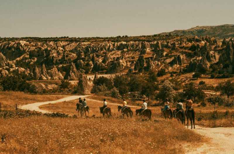 a group of people riding horses down the road