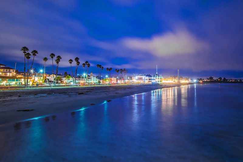 a beach at night with palm trees and buildings