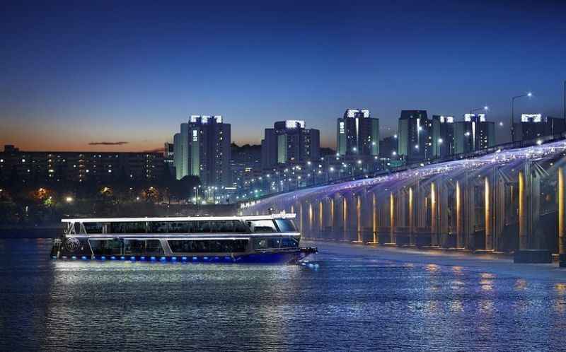 a boat traveling down the river in front of a city