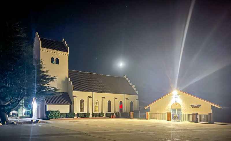 a church lit up at night with a street light