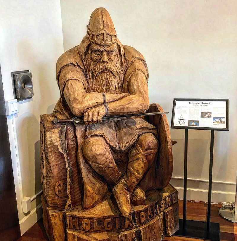 a wooden sculpture of an old man sitting on a chair