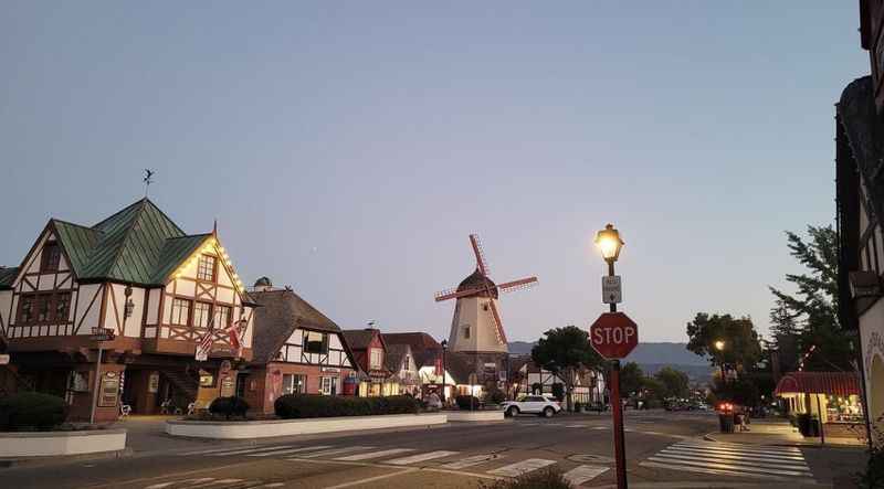 a street with a windmill and buildings in the background