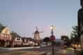 a street with a windmill and buildings in the background