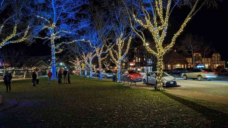 people walking down the street at night with christmas lights