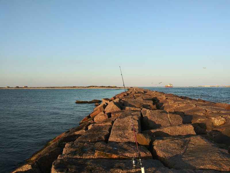 a large rock in the water near a lighthouse