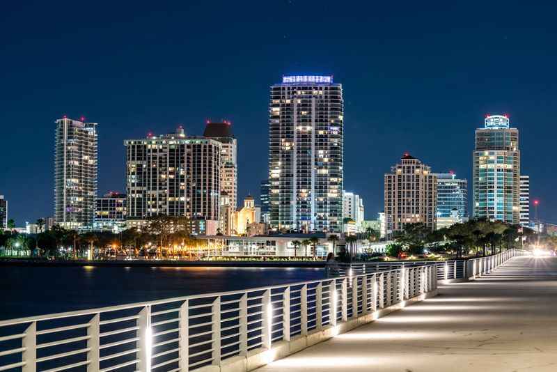 a long white bridge towards the city at night