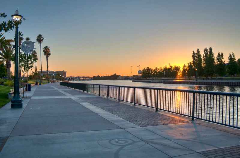 a sidewalk next to a lake at dusk