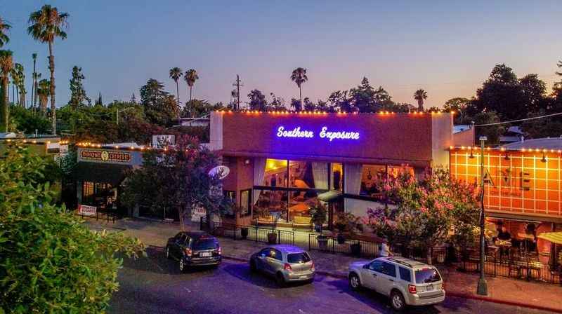 the outside of a restaurant with cars parked in front