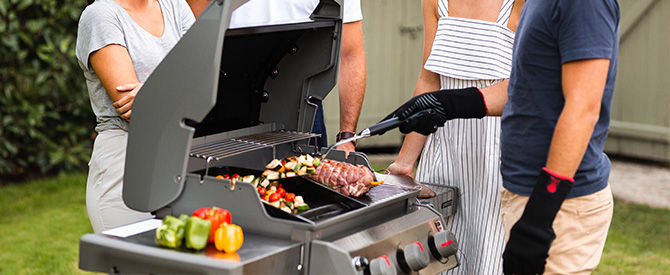 Personnes cuisant un gigot au barbecue à gaz