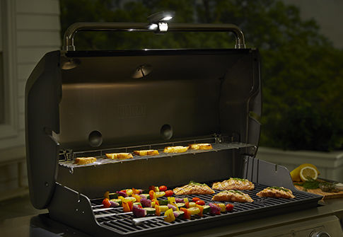 Grand barbecue à couvercle avec de nombreux aliments en train de cuire