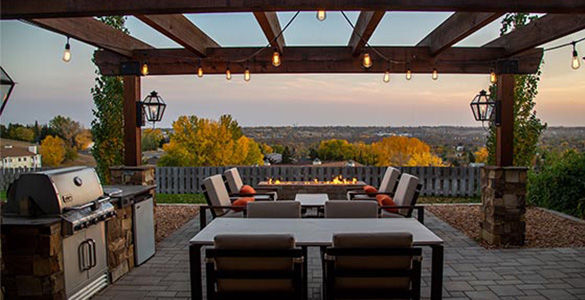 Cuisine extérieure sous une pergolas avec table et chaise durant un coucher de soleil