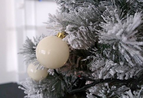Boule de Noël blanche accrochée à un sapin enneigé